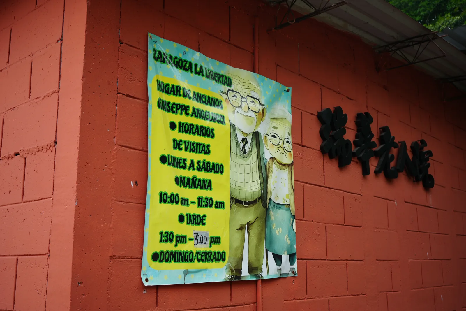 Entrance signage of Hogar de Ancianos Giuseppe Angelucci showing visiting hours.