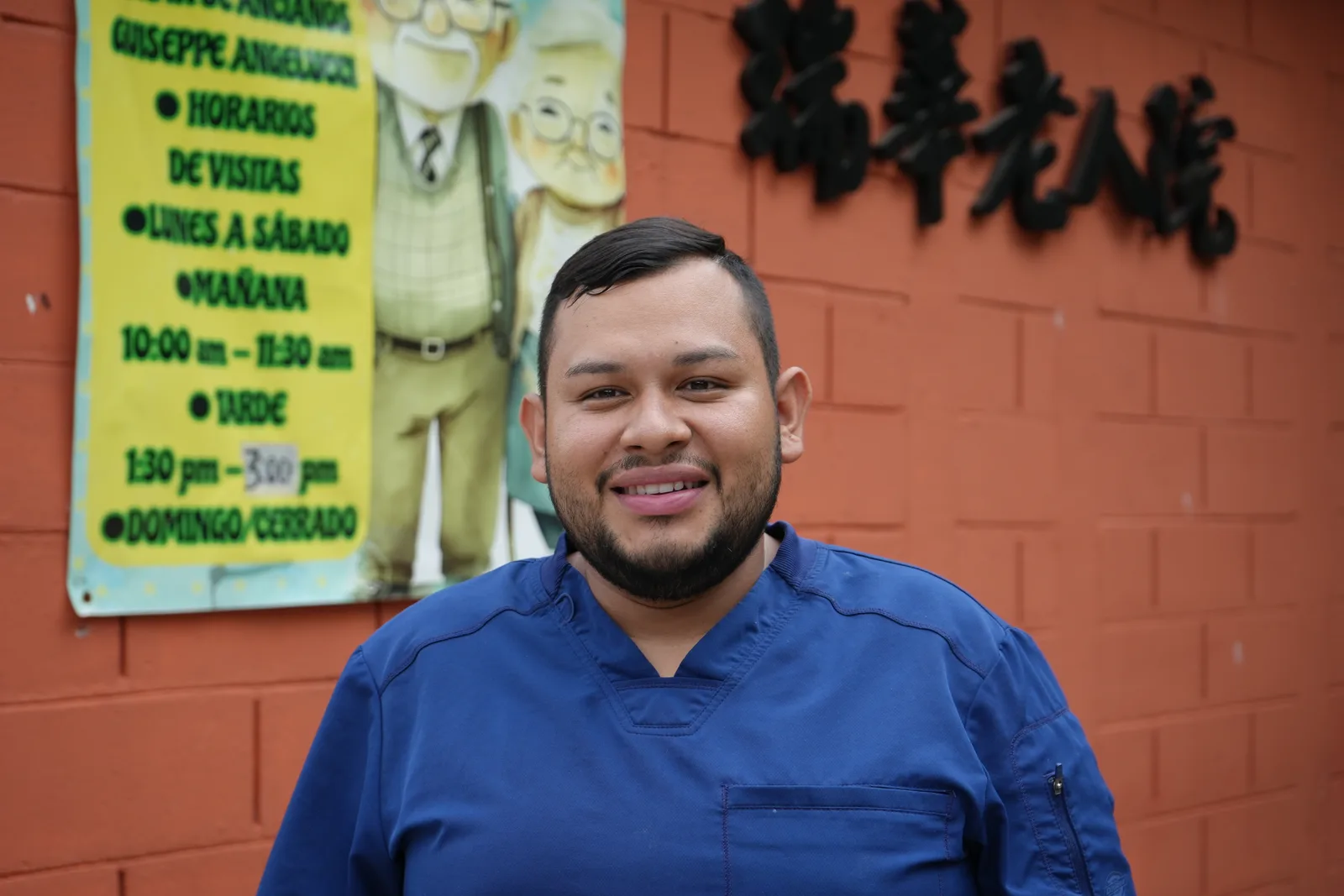 Cristian, Nurse, in front of the home's signage.